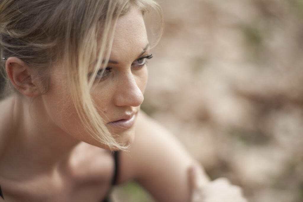 A blonde woman looking thoughtfully to the side during her skincare routine for dry skin.